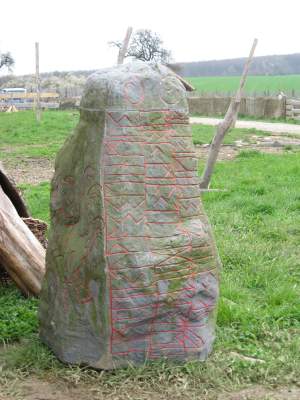 Stein mit eingeritzten und rotgefärbten Runen, der sich nicjt ohne Grund anfühlt wie aus Plastik - er ist eine moderne Nachbildung